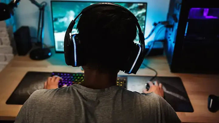 Ein Junge sitzt vor einem Gaming-PC und trägt Kopfhörer 