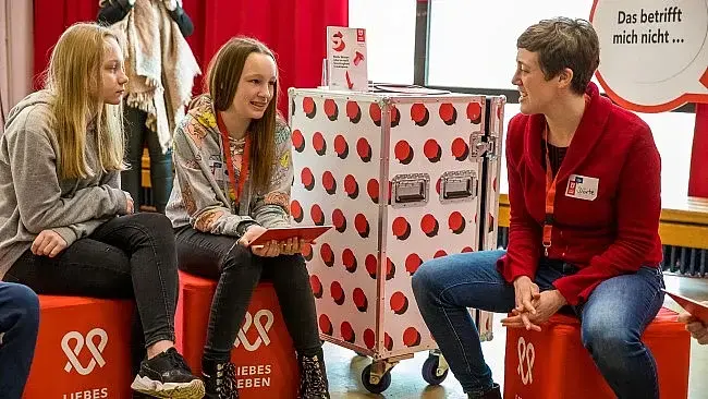 zwei junge Frauen im Gespräch mit einer Moderatorin
