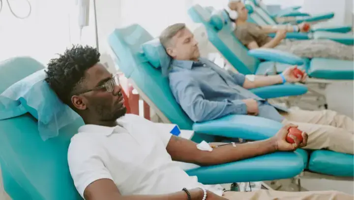 Eine Reihe von türkisen Liegen, auf denen Menschen liegen, die Blut spenden.