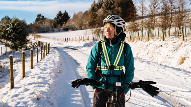 Frau mit Fahrrad in einer Winterlandschaft