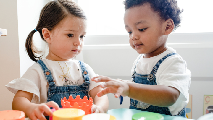 Zwei Kleinkinder, ein Mädchen und ein Junge spielen mit Stapelbechern.