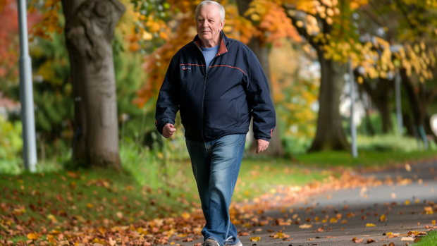 Älterer Mann spaziert durch einen herbstlichen Park.